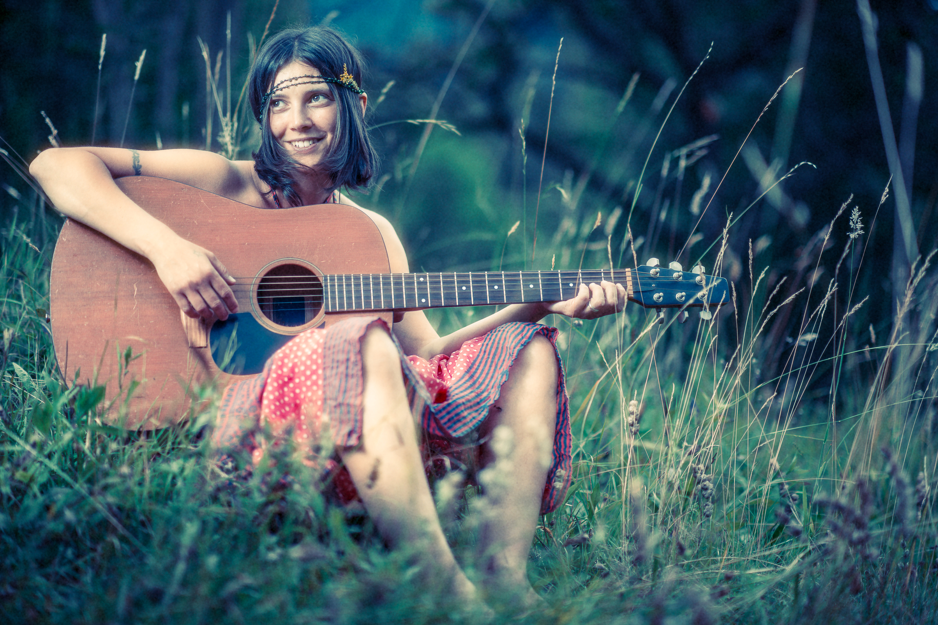 Kobieta w stylizacji hipisowskiej gra na gitarze