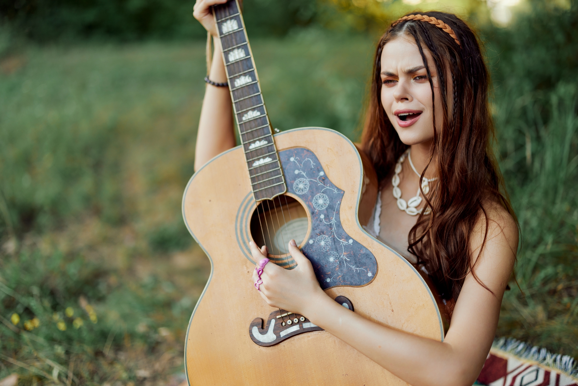 Kobieta gra na gitarze i ubrana jest w stylu hippie
